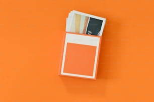 une boîte de cartes orange et blanches sur fond orange