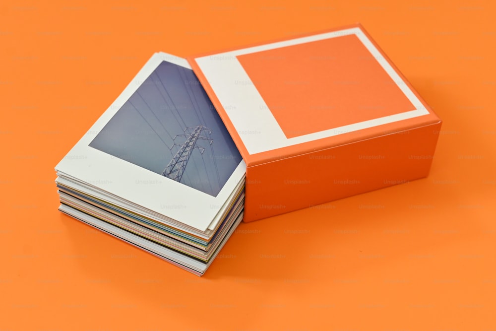 a stack of photographs sitting on top of an orange surface