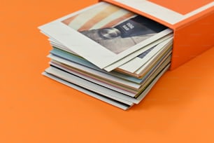 a stack of magazines sitting on top of an orange table