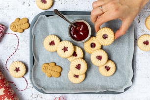a tray of cookies with jam being drizzled on them