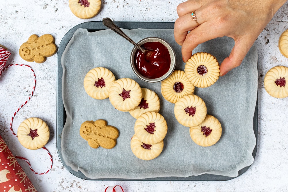 a tray of cookies with jam being drizzled on them