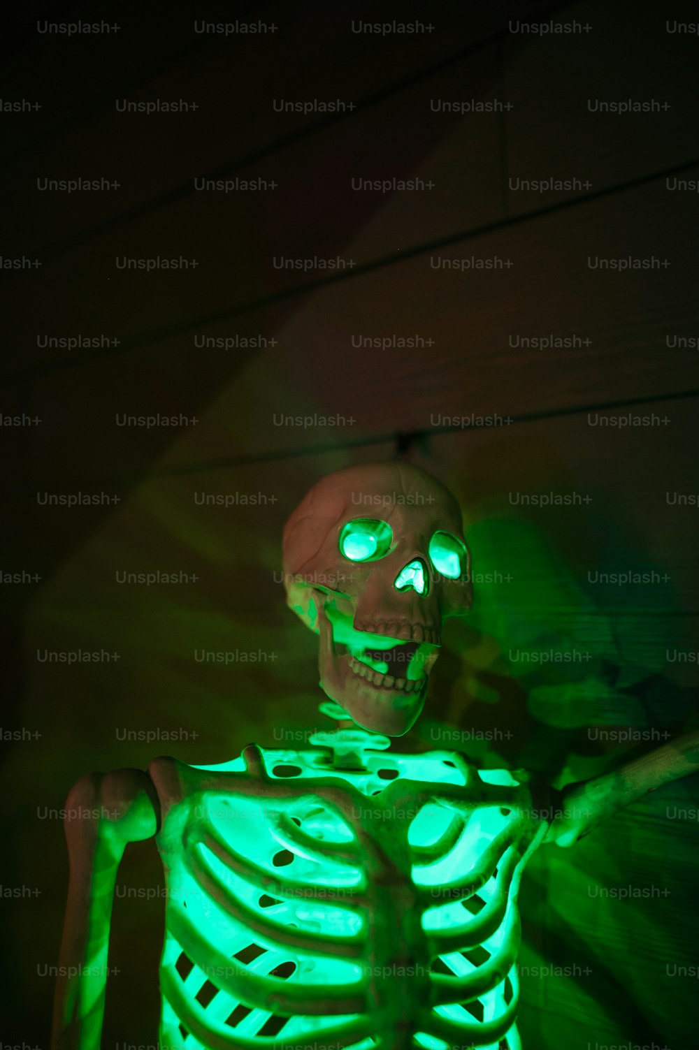 um esqueleto com olhos verdes brilhantes em um quarto escuro