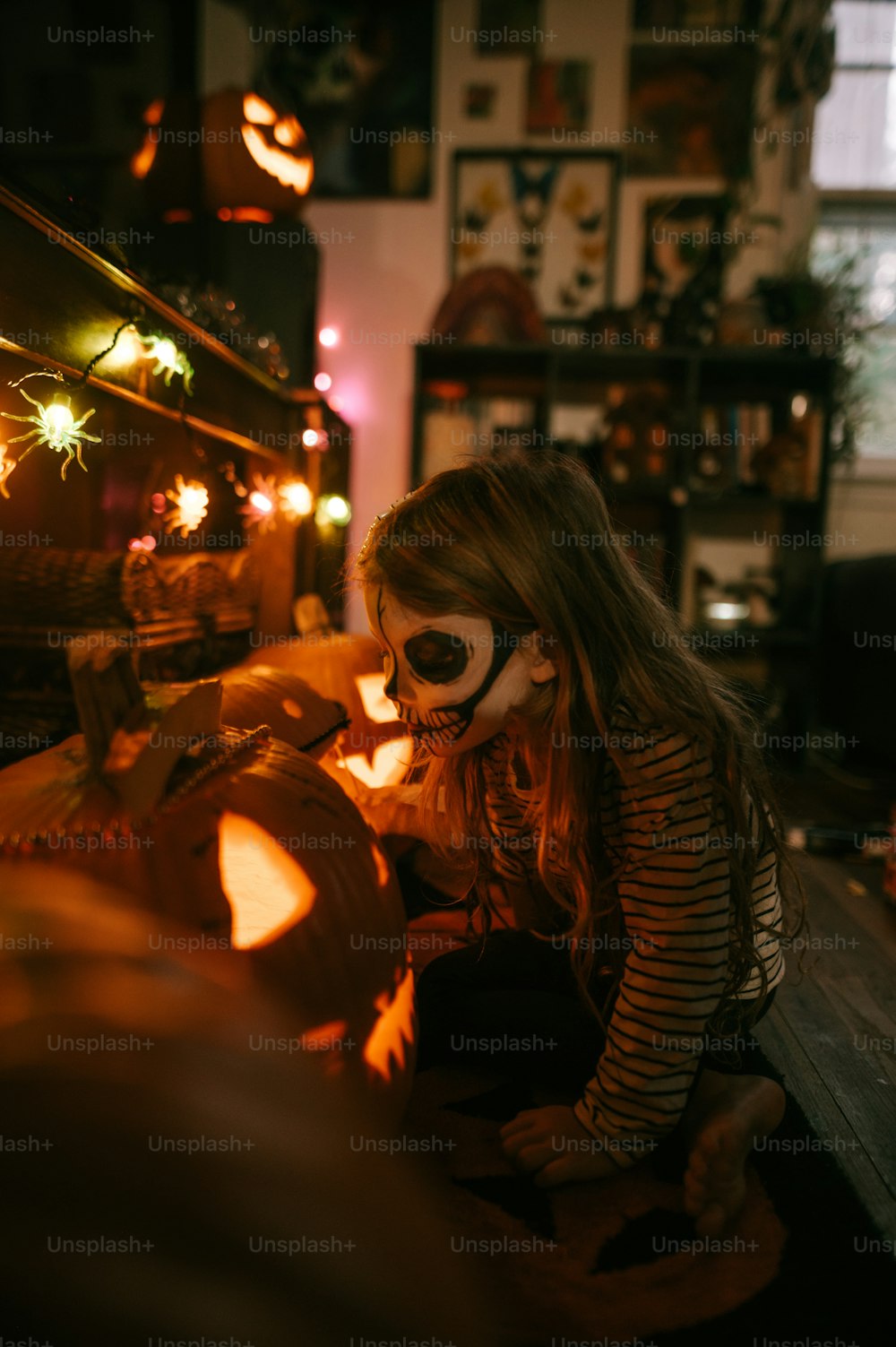 une jeune fille dans un masque de squelette décorant une citrouille