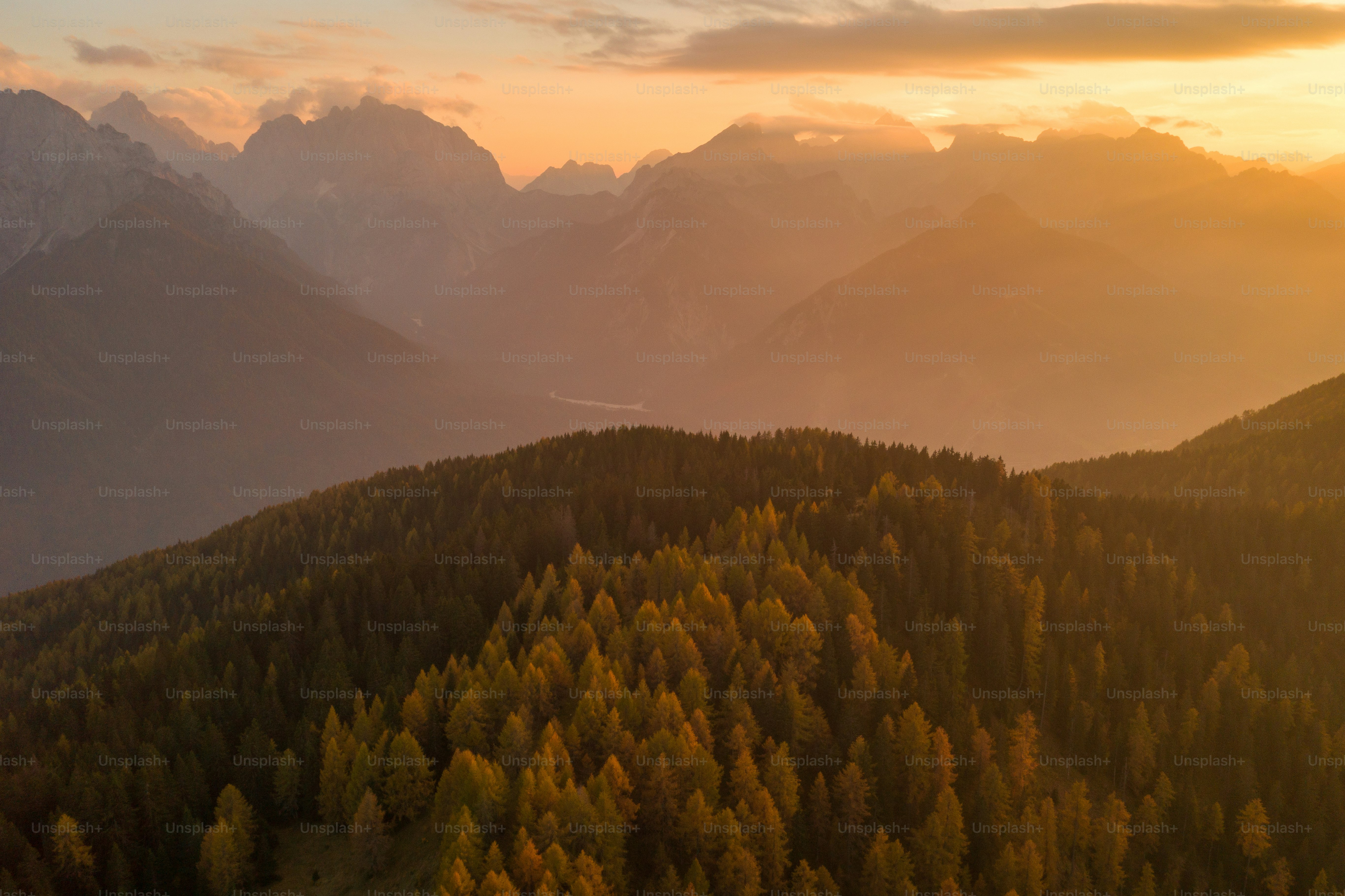 the sun is setting over the mountains and trees