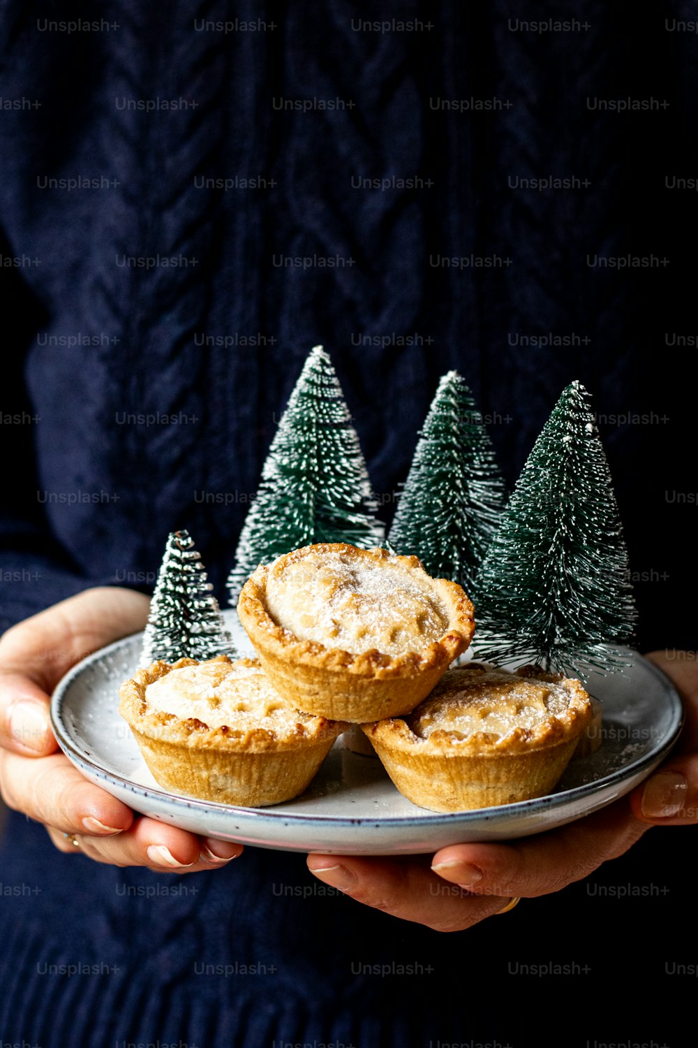 a person holding a plate with mini christmas trees on it