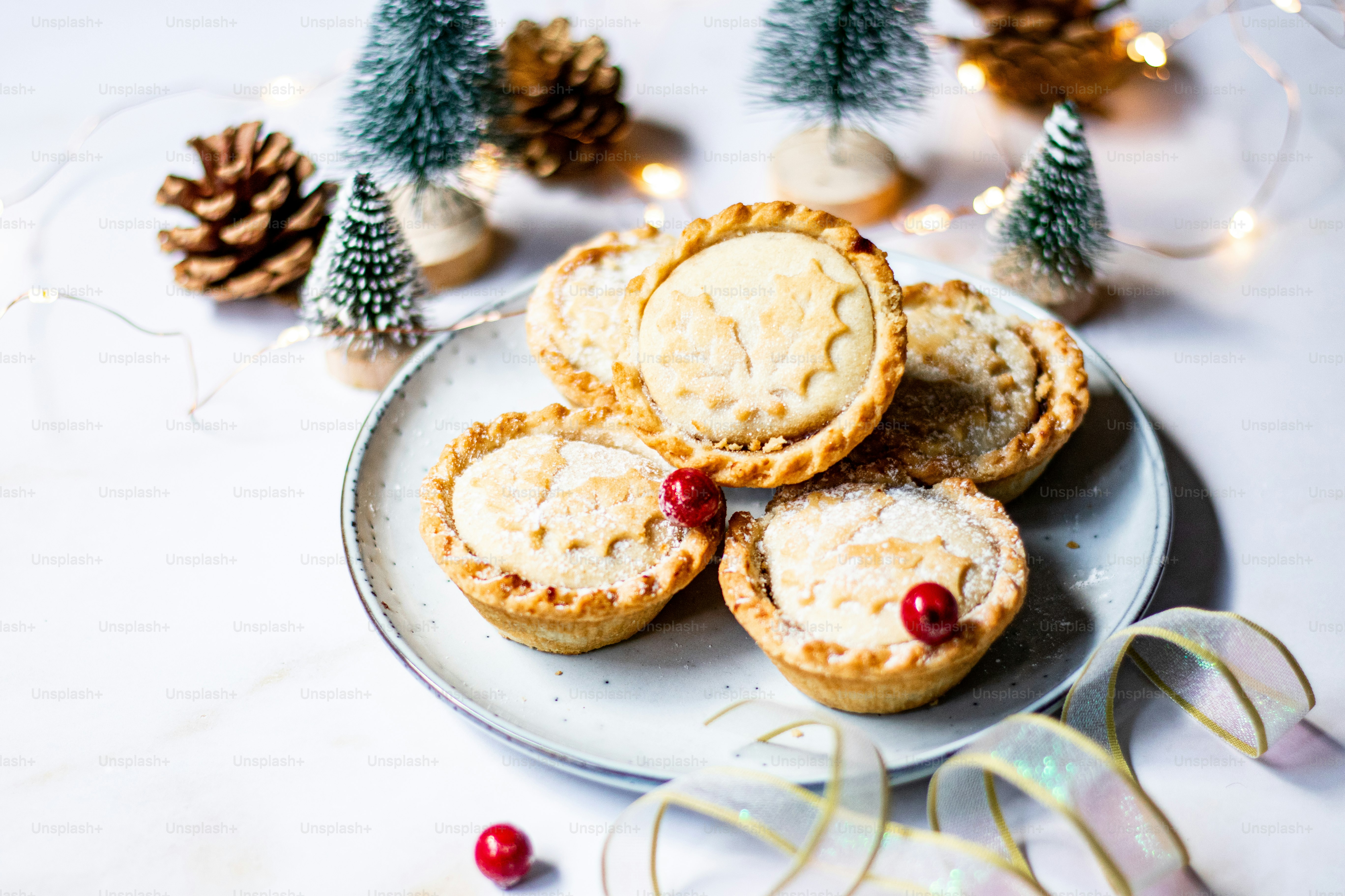 a white plate topped with mini pies next to a christmas tree