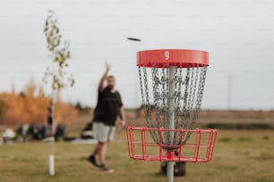 Um homem jogando um Frisbee em uma cesta de golfe Frisbee