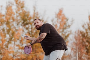 um homem segurando um frisbee roxo em sua mão direita