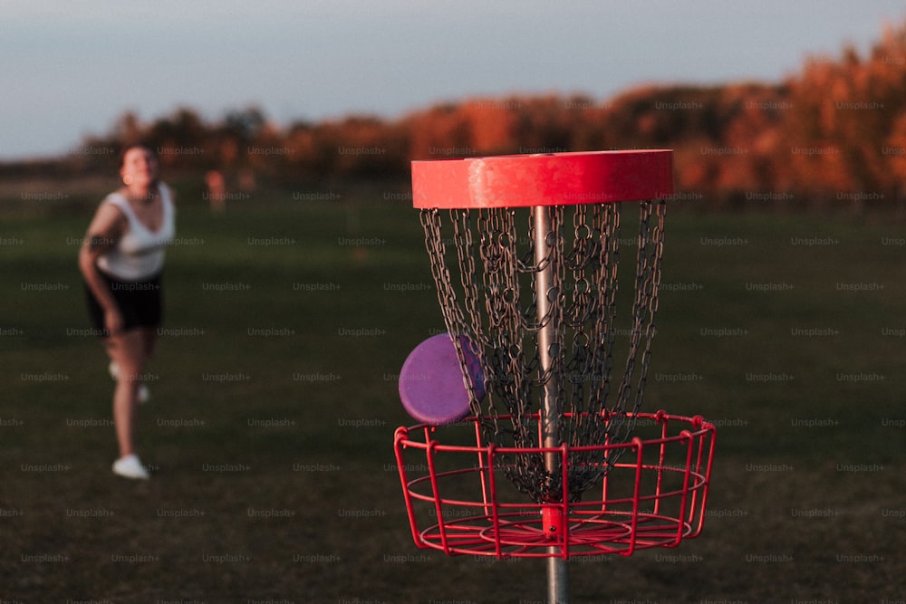 uma mulher jogando um frisbee em uma cesta de golfe frisbee