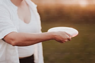 uma mulher segurando um frisbee branco em sua mão