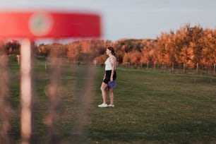 a woman standing in a field with a frisbee