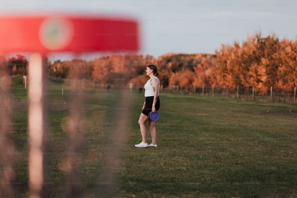 a woman standing in a field with a frisbee