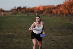 una mujer sosteniendo un frisbee púrpura en la parte superior de un campo