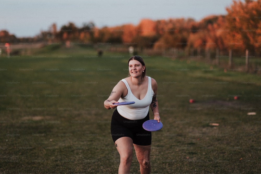 a woman holding a purple frisbee on top of a field