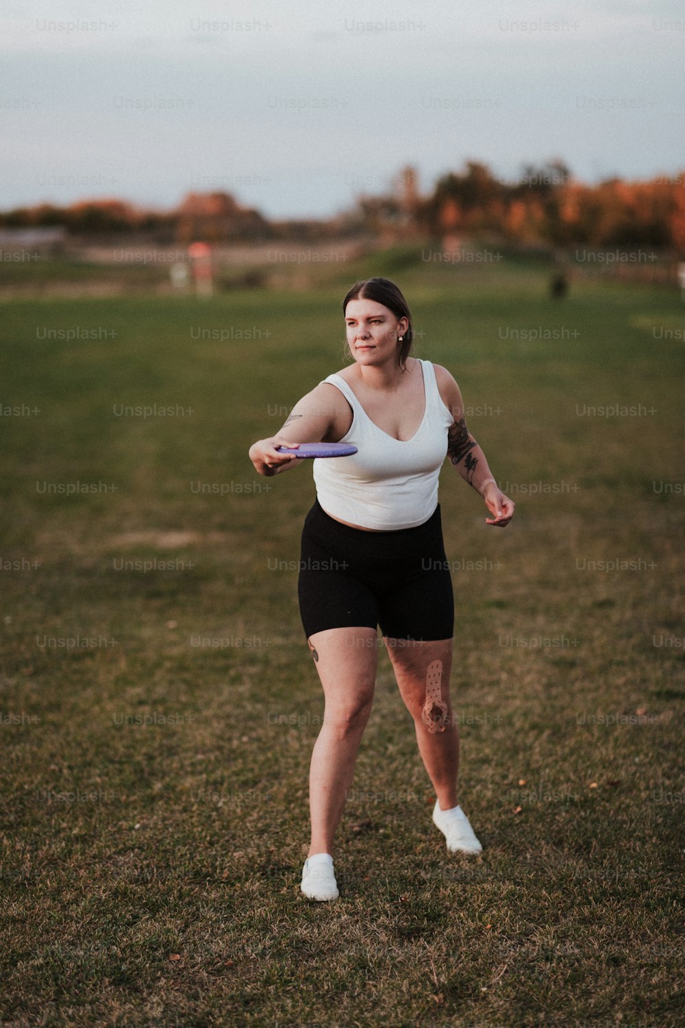 eine Frau steht auf einem Feld und hält eine Frisbee in der Hand