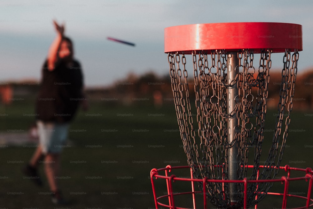 um homem jogando um frisbee em uma cesta de metal