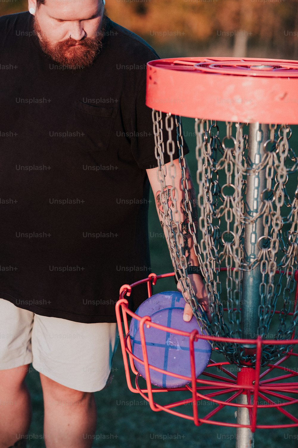 a man holding a frisbee in front of a frisbee golf net