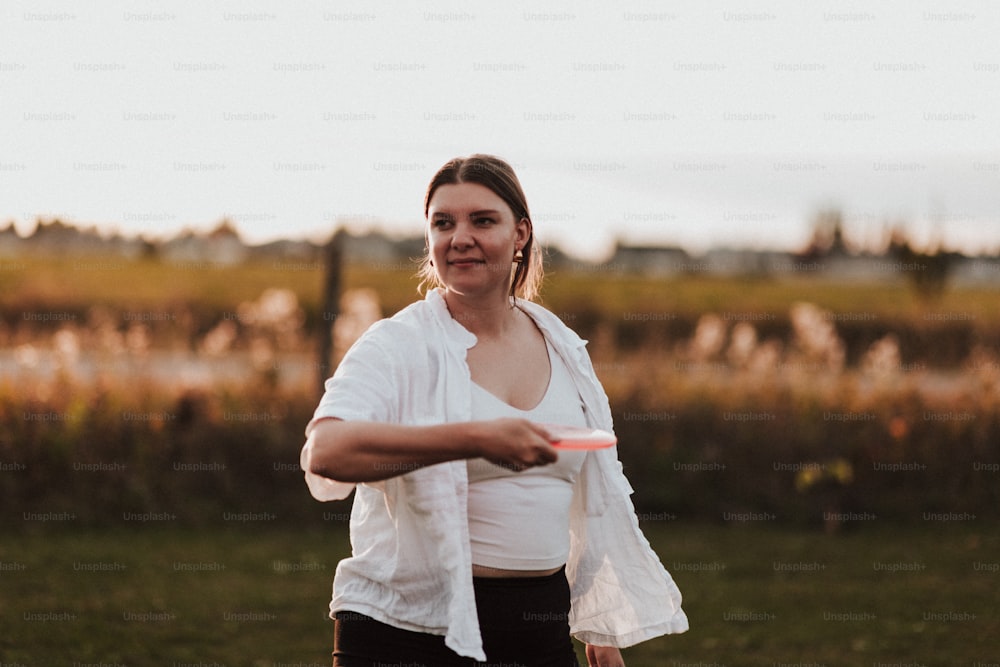 a woman holding a red frisbee in a field