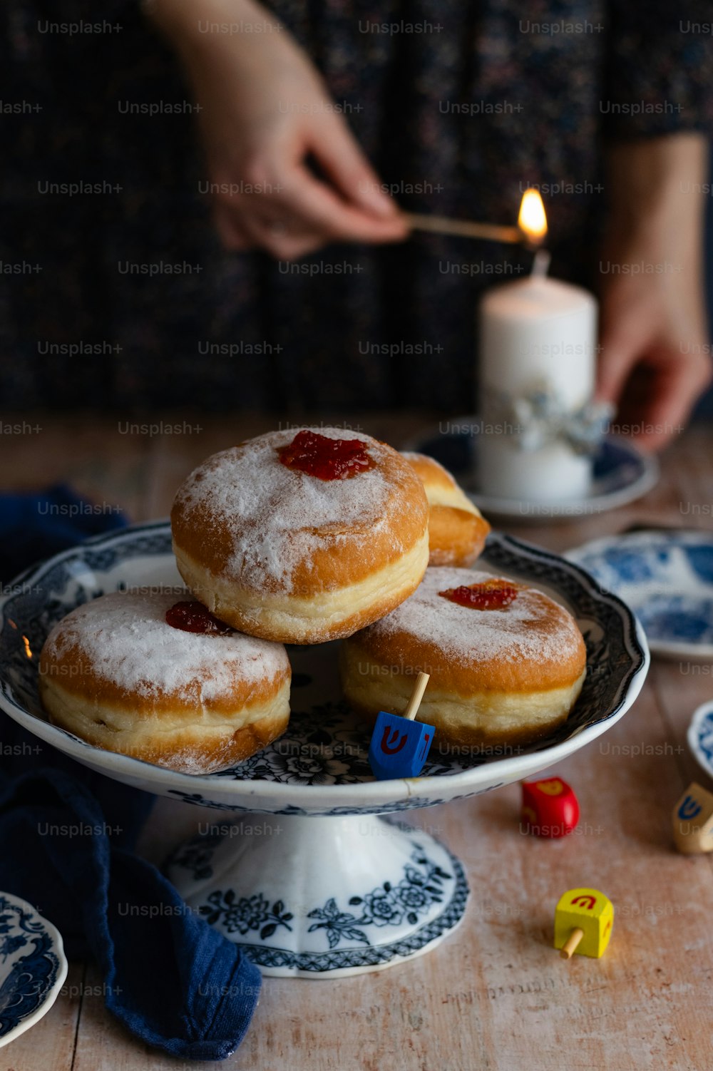 a person lighting a candle on a plate of donuts
