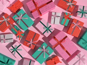 a pile of colorful wrapped presents on a pink surface