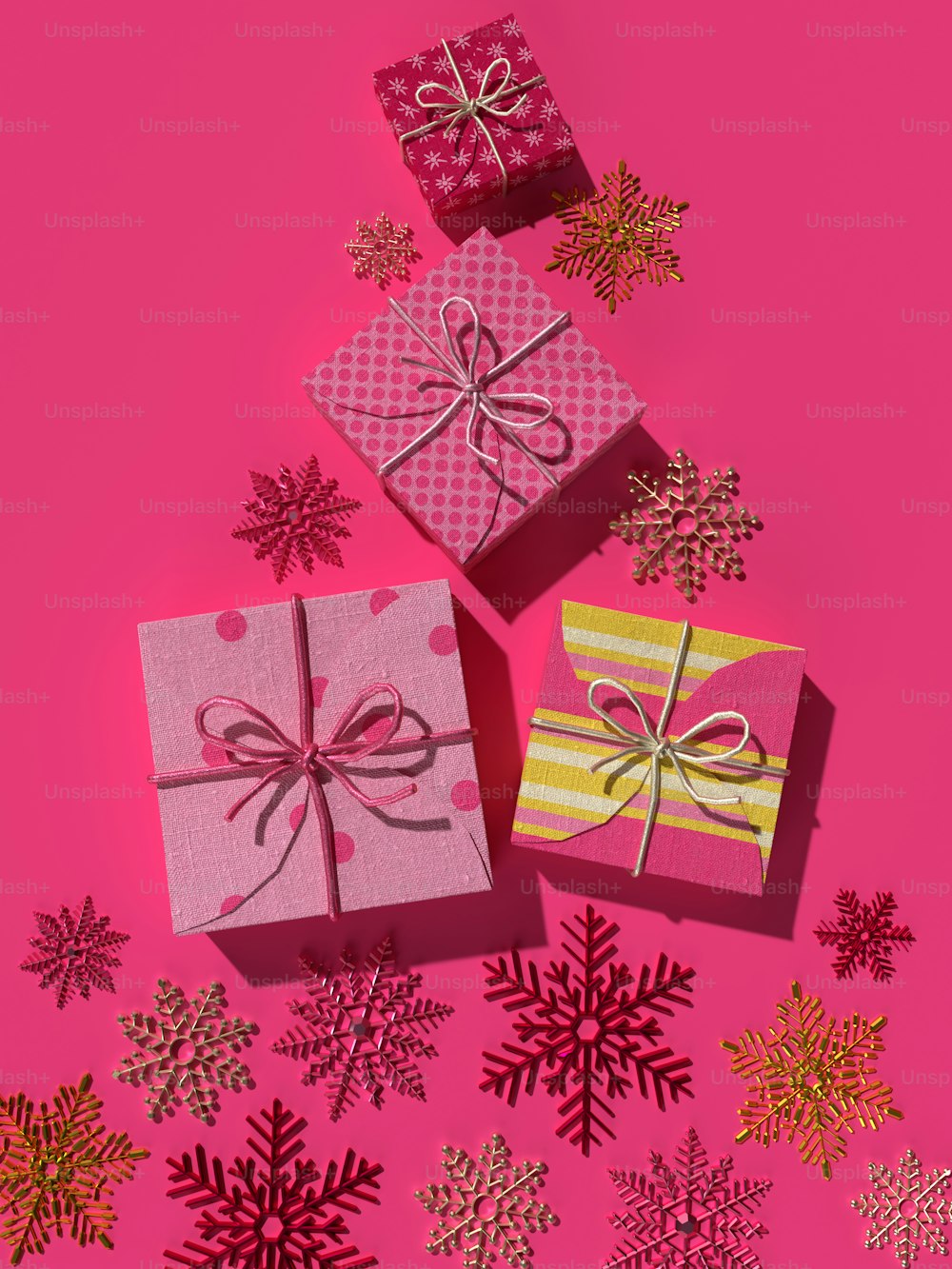 three wrapped presents on a pink background with snowflakes