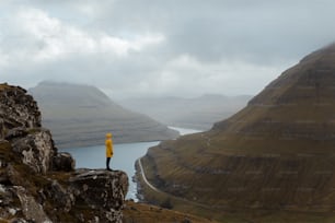 une personne en veste jaune debout sur une falaise