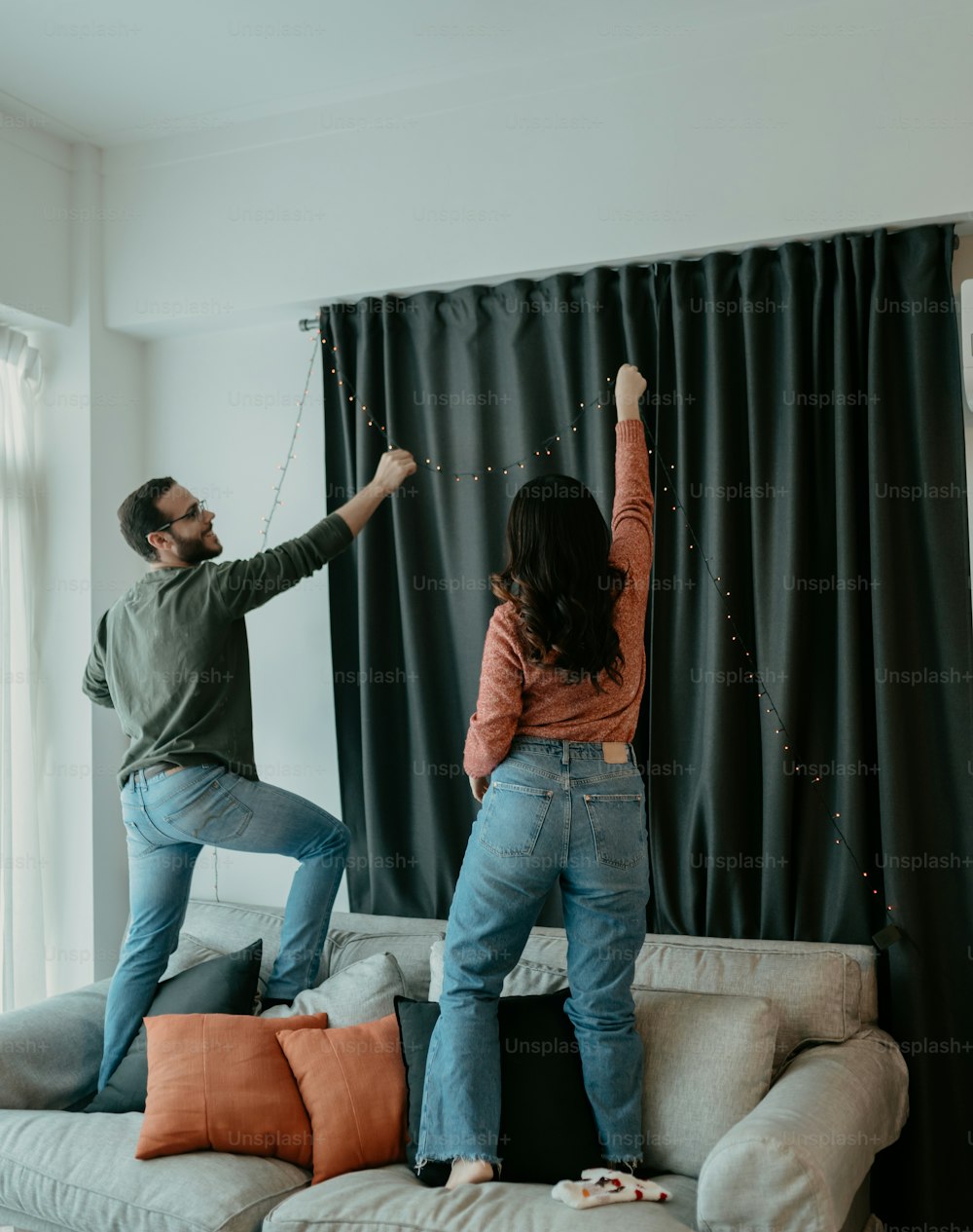 a man and a woman standing on top of a couch