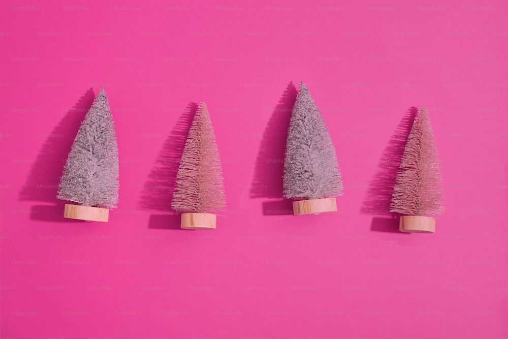 un gruppo di tre piccoli alberi seduti in cima a una superficie rosa