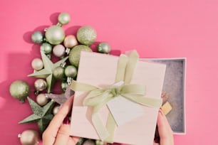 Una persona abriendo una caja de regalo con un lazo verde