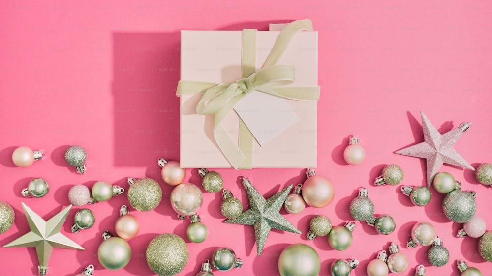 Una scatola bianca con un fiocco verde circondato da ornamenti natalizi