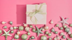 Une boîte blanche avec un nœud vert entourée d’ornements de Noël