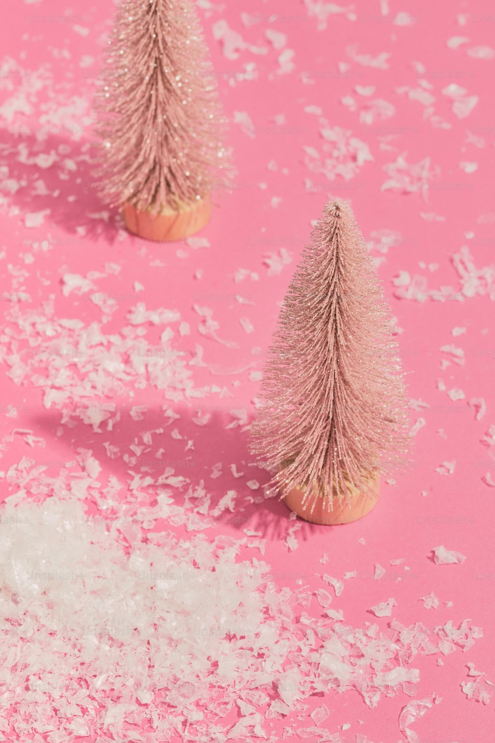 Tres pequeños árboles de Navidad rosas sobre un fondo rosa
