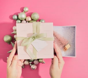 Una persona abriendo una caja de regalo con una cinta verde