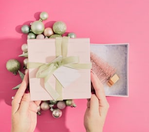 a person opening a gift box with a green ribbon