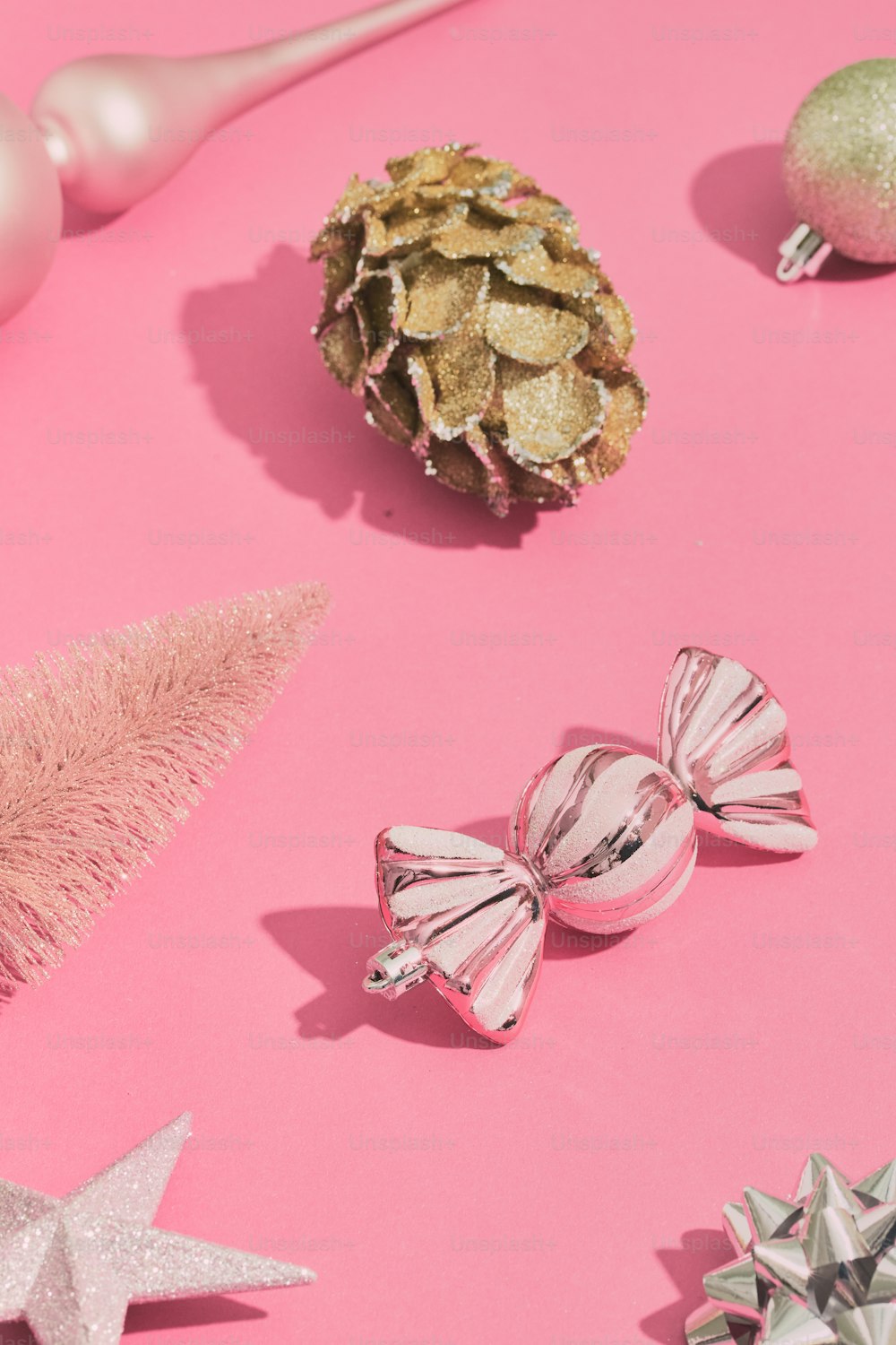 a pink table topped with christmas ornaments and a pine cone