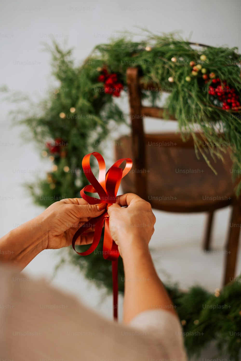 a woman holding a red ribbon in front of a wreath