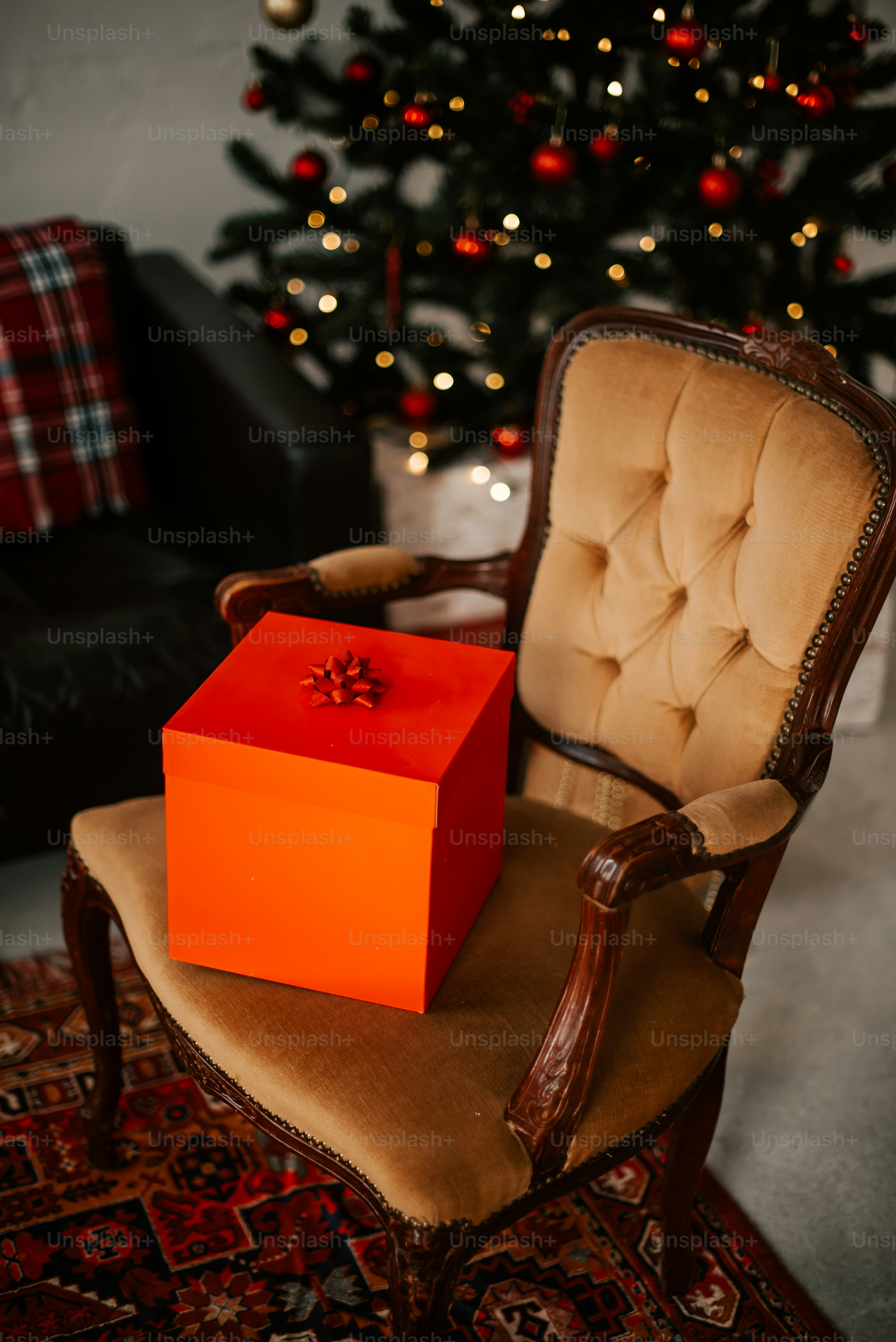a chair with a present box on it in front of a christmas tree