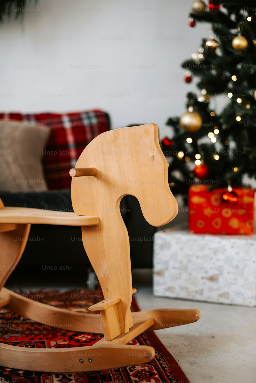 Un caballito balancín de madera junto a un árbol de Navidad