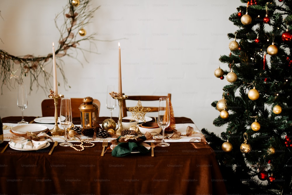 a table set for christmas dinner with a christmas tree in the background