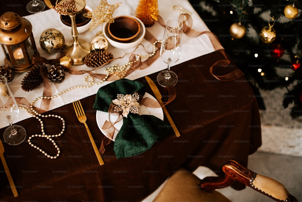 a table set for a holiday dinner with a christmas tree in the background