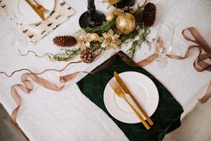 a table set for a holiday dinner with gold and green decorations