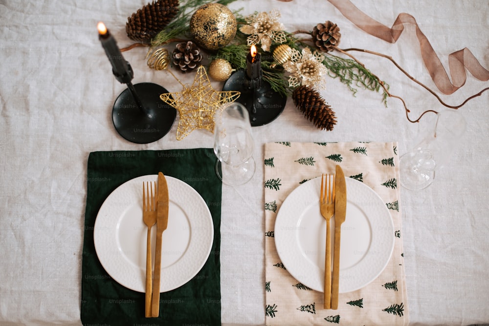 a table set for christmas dinner with pine cones and candles
