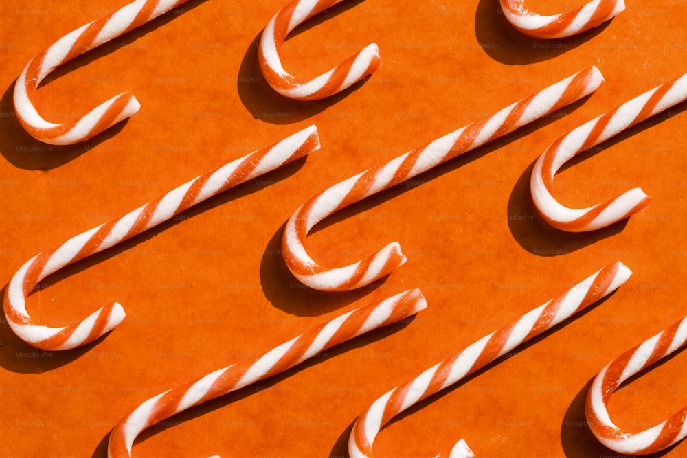 a group of candy canes sitting on top of an orange surface