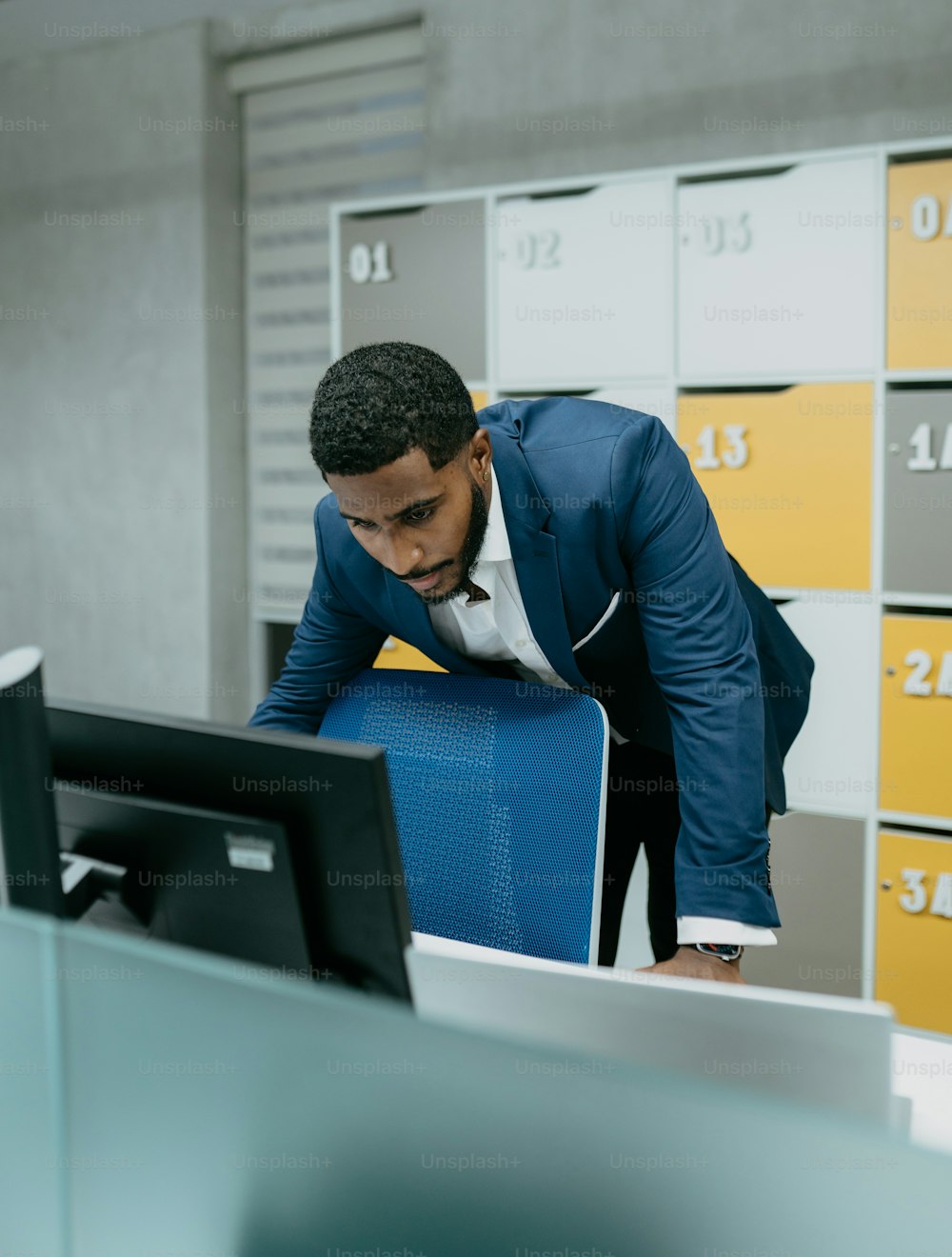 a man in a suit leaning over a computer monitor