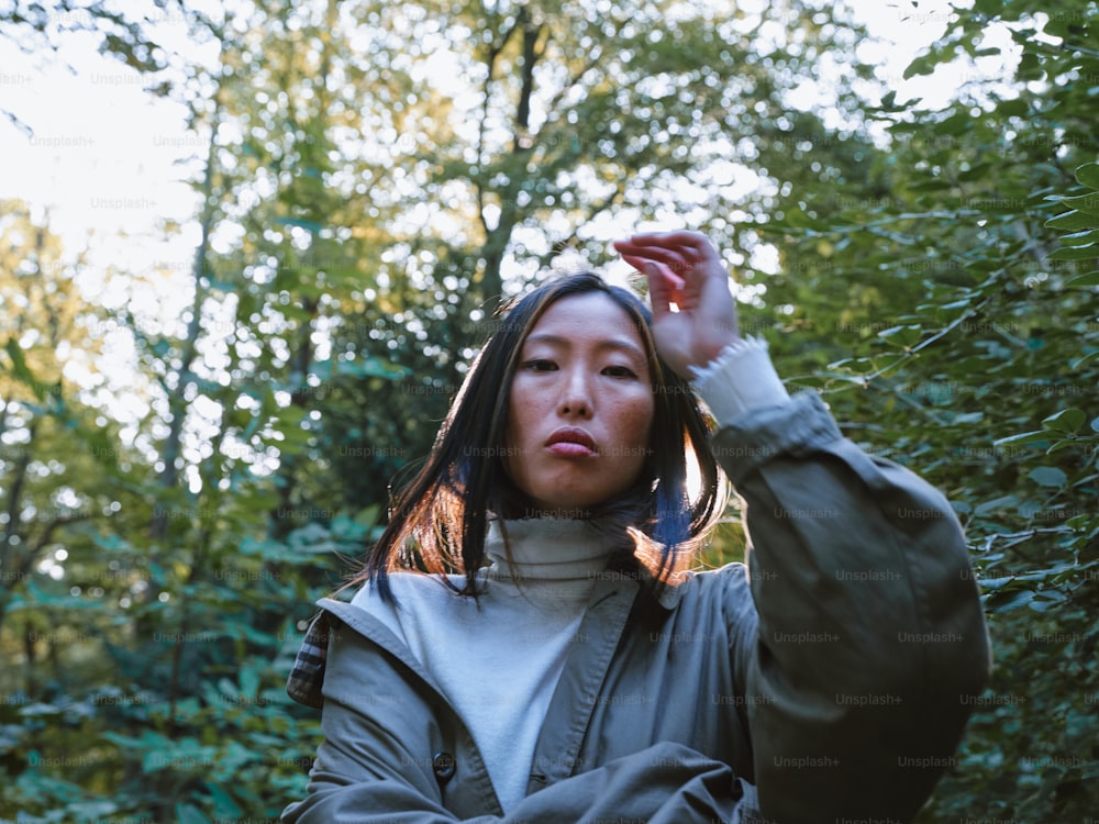 a woman standing in front of a forest holding a cell phone to her ear