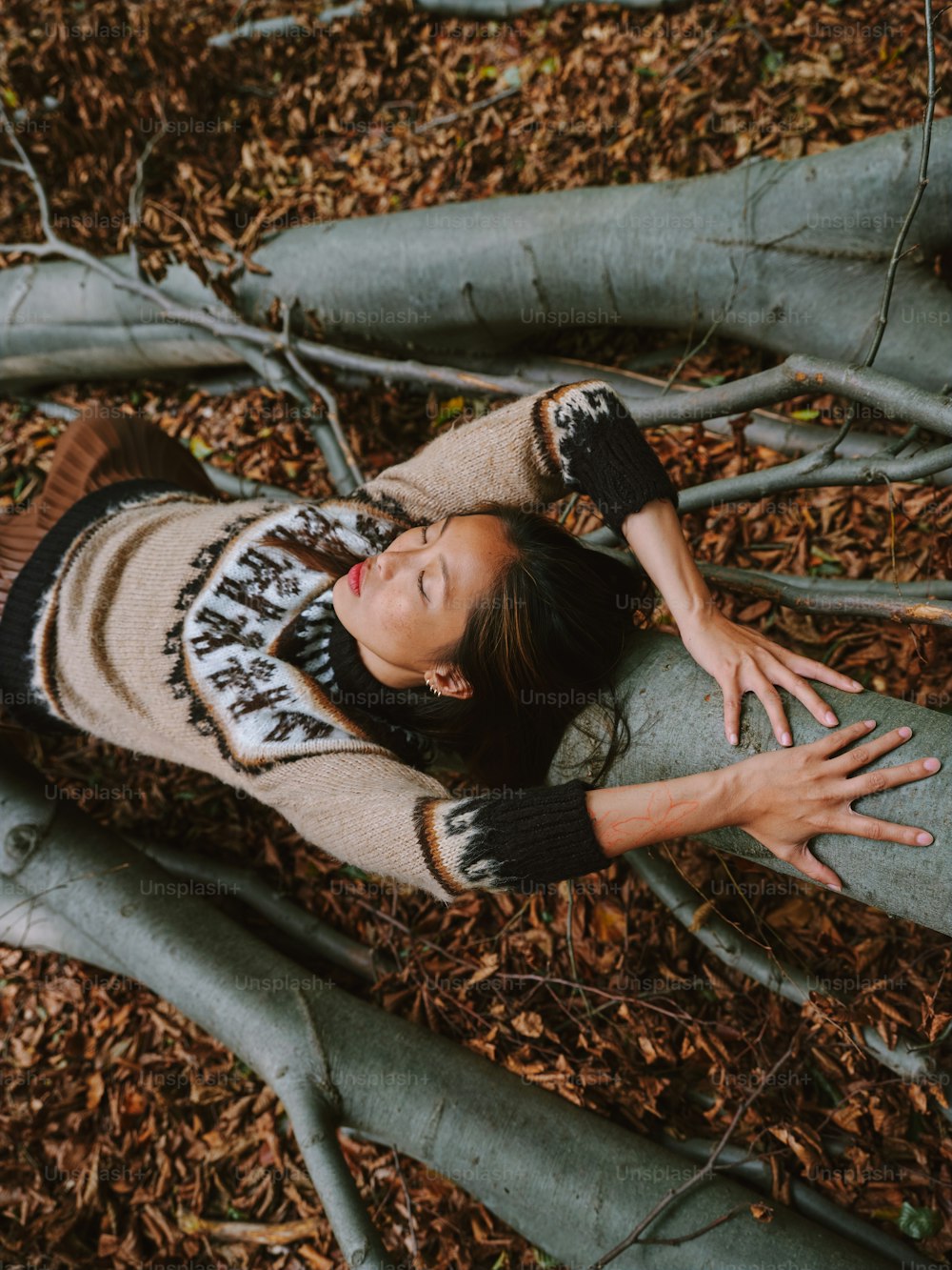 a woman laying on the ground next to a tree