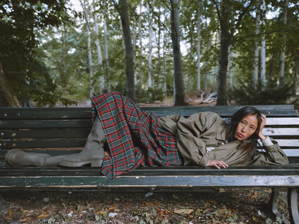 uma mulher deitada em um banco em um parque