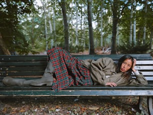 Una donna che si trova su una panchina in un parco