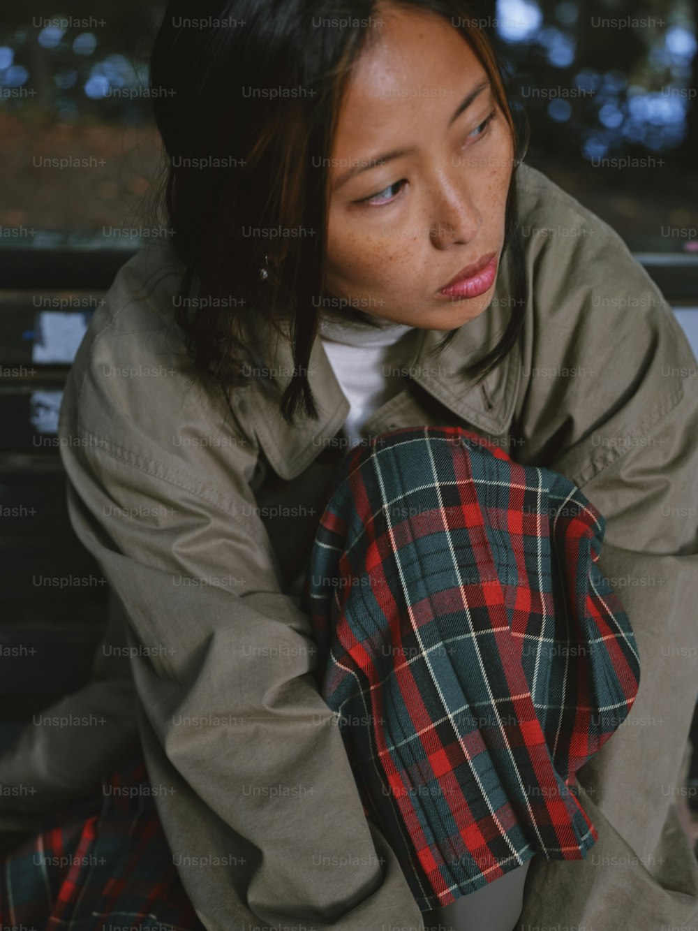 a woman sitting on a bench wearing a plaid shirt