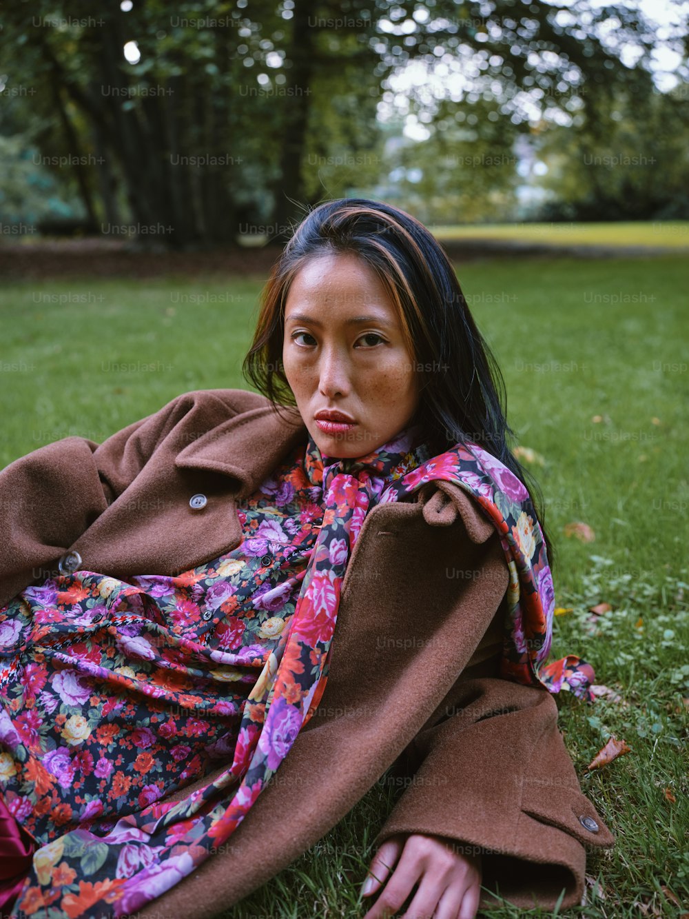 a woman sitting in the grass with a blanket over her